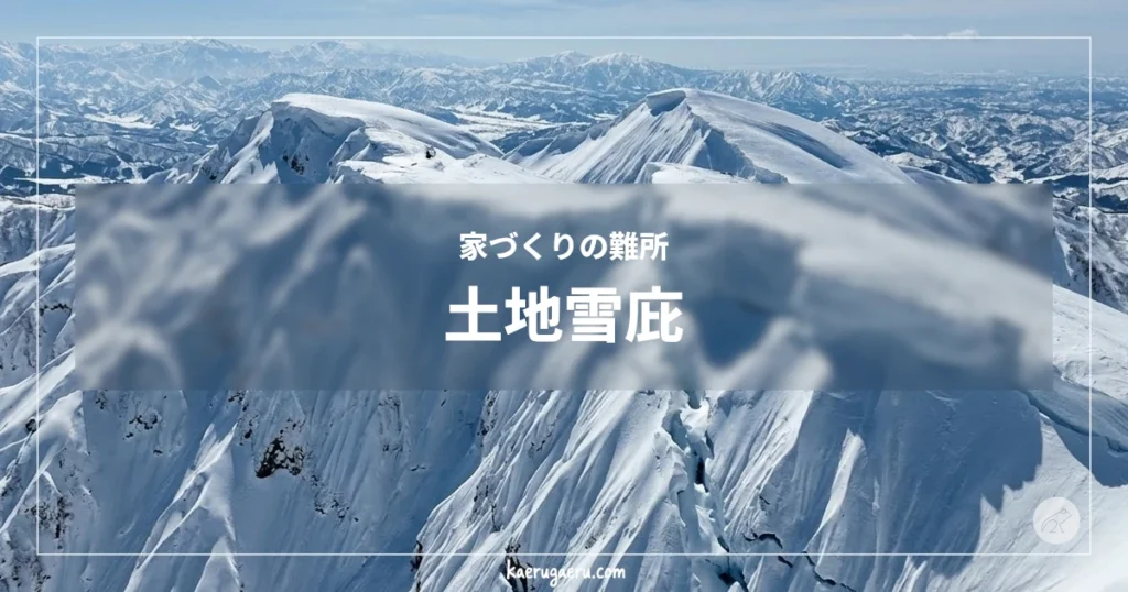 家づくりの難所 土地雪庇。青空の下、巨大な雪庇が形成された険しい雪山の稜線と、遠くに連なる山々。