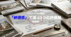 デスクの上に整然と並べられた「HOME DESIGN GUIDE 2026」や「PHASE PLANS」といった住宅設計のパンフレットや資料。中央には「ハウスメーカー選び 『納得感』で選ぶ5つの評価軸【総集編】」という文字タイトルが透過帯に配置され、その奥に手書きのレーダーチャートや「Unlock」、「Future-Proof」といったメモ、そして方位磁針と木製の定規が置かれている。家づくりの戦略的な比較検討を象徴するスタイリッシュな作業風景。